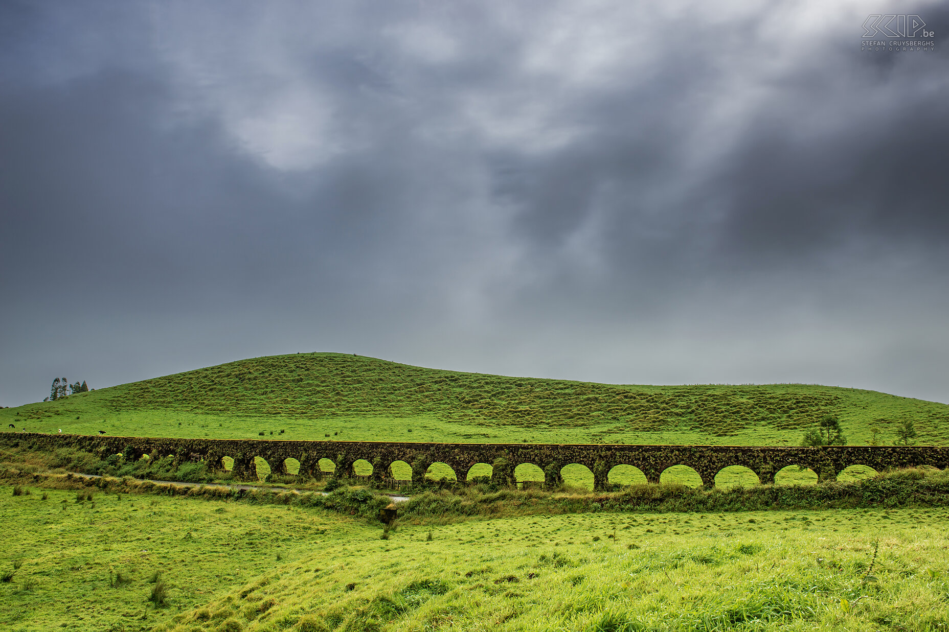 Aquaduct - Muro das Nove Janelas The aqueduct 'Muro das Nove Janelas' (wall of the nine windows) is situated at a height of 760meter near Caldeira das Sete Cidades on the western coast of Sao Miguel. This Muro is an ancient aqueduct that transported water to the capital Ponta Delgada. The aqueduct is over 100 years old, not used anymore but still intact. The weather at the Azores is very changeable. The islands are located far out in the Atlantic Ocean so rain showers can happen every moment of the day. The temperatures varies between 12 to 26 °C. Stefan Cruysberghs